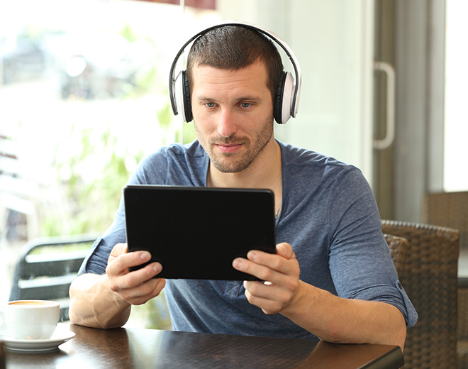 jeune homme avec casque audio devant une tablette numérique